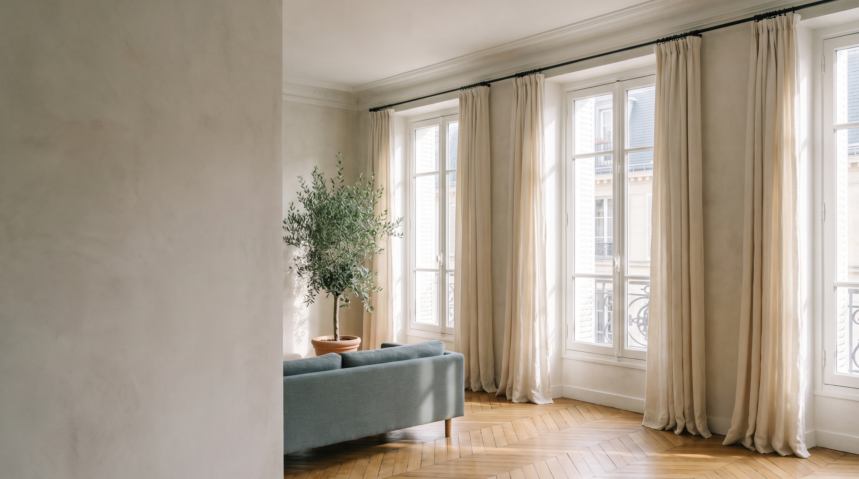 Salon parisien aux grandes fenêtres habillées de rideaux en lin écru